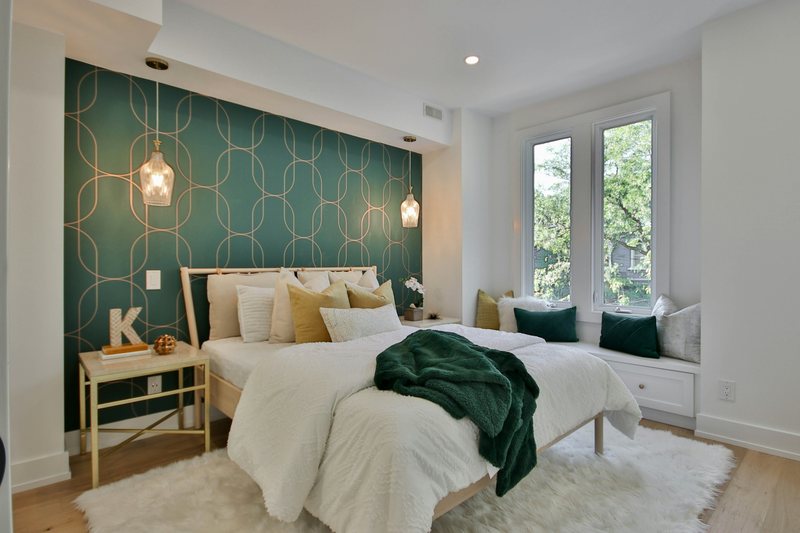 Bright bedroom with an emerald feature wall printed with a gold interlocking-arch pattern behind the bed